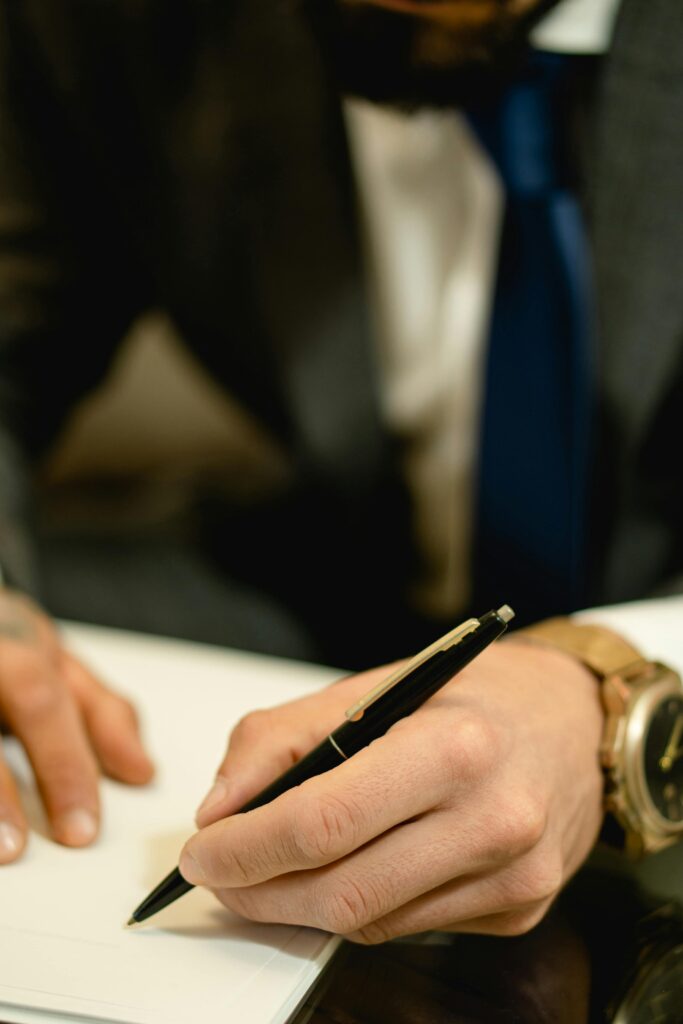 pexels photo 7504780 7504780 Close-up of hand signing a legal contract with a pen. Ideal for business and legal themes.